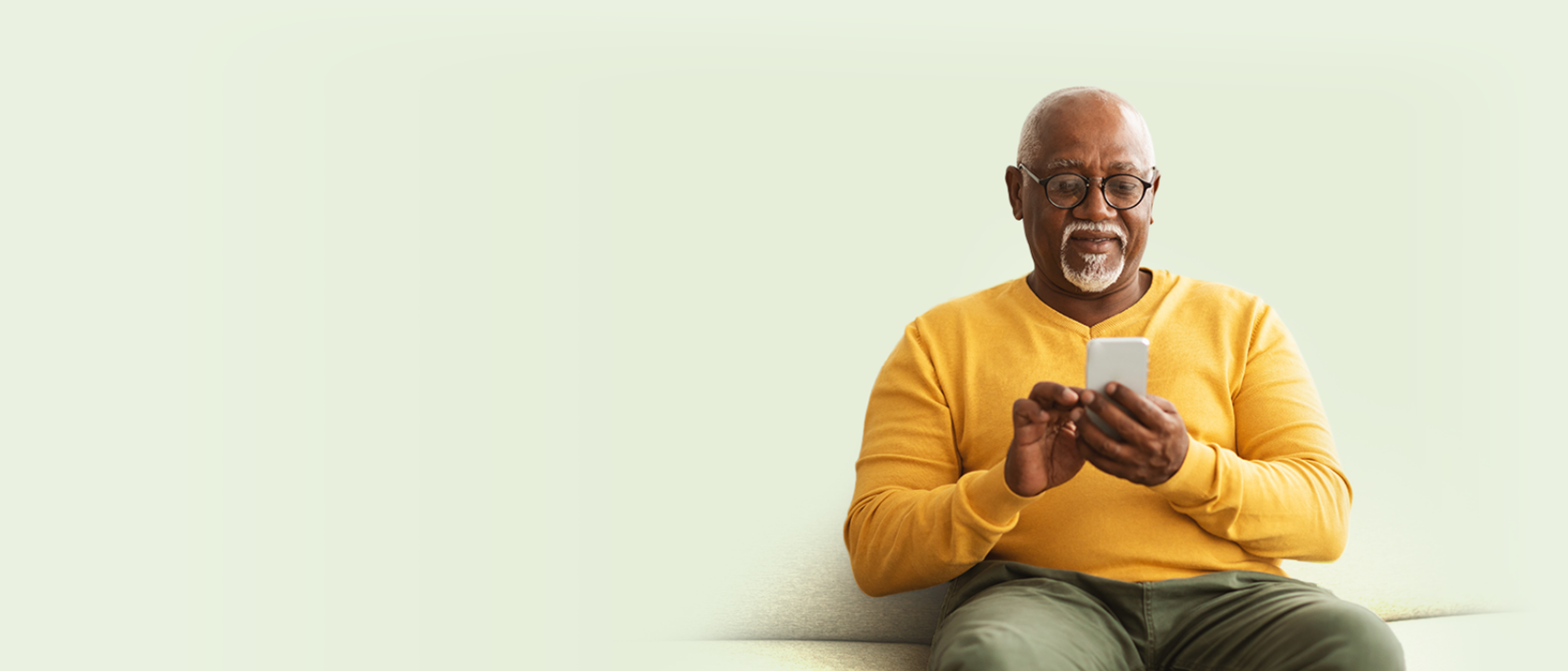 Man in yellow jumper searching for Fond Farewell Cremations on his mobile phone.
