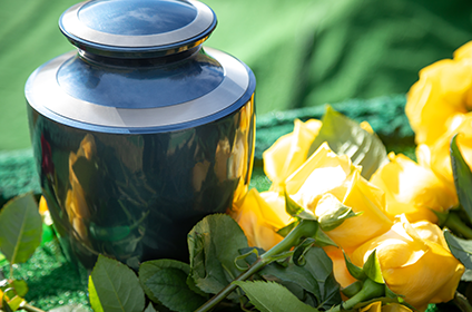 A black urn resting next to with yellow roses.
